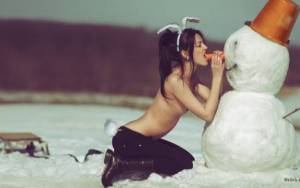 Девушка топлес зимой кусает морковку снеговика