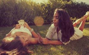 Девушки играют в карты на траве