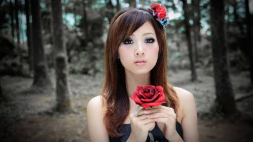 Азиатка в лесу с красной розой в руке